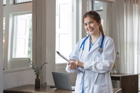 Smiling female doctor holding a clipboard with information and patient care documents. and stethoscope in the doctors office in the hospitalの写真素材