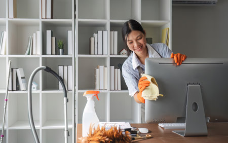 Young woman uses a cleaning cloth to disinfect the computer and equipment on the office table....