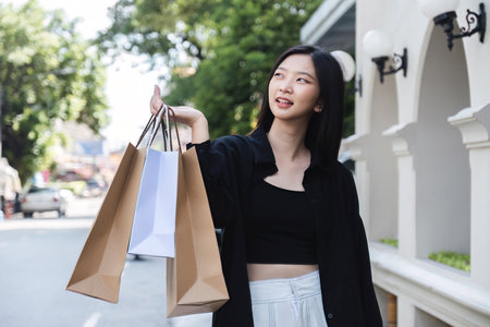 young Asian woman holding shopping bags on Black Friday while standing in the mall area copy spaceの写真素材