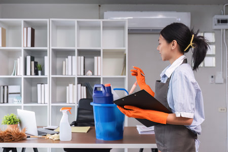 Young woman standing and checking cleaning item or cleaning supplies in office Cleaning staff or maid cleaning the officeの写真素材