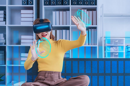 Attractive Asian woman play game in virtual reality through VR glasses on the sofa having fun and...