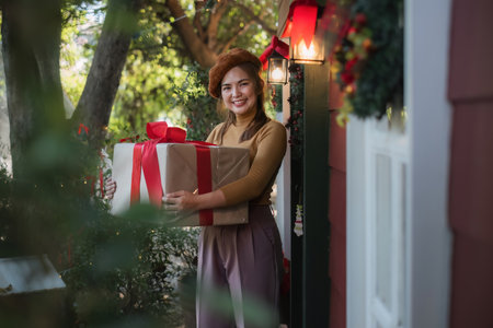 Merry Christmas A beautiful young woman dressed in a Christmas look is decorating the Christmas tree and lights in the house in preparation for a holiday party. Christmas at homeの写真素材