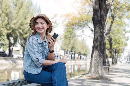 Young Asian tourist walking along city streets and holds a mobile phone on the pavement