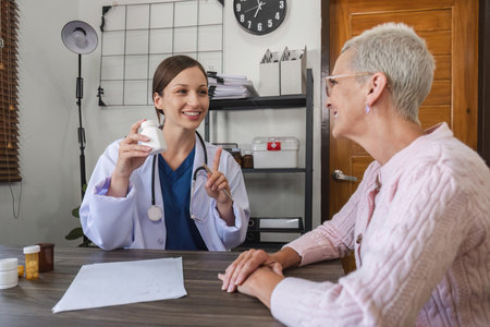 Female doctor in white coat talking with elderly patient in clinic, giving advice on health and...