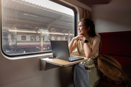 Young Asian woman uses a laptop while sitting on a train.