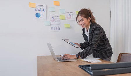 Professional Asian business woman intent on work focusing on laptop in modern office