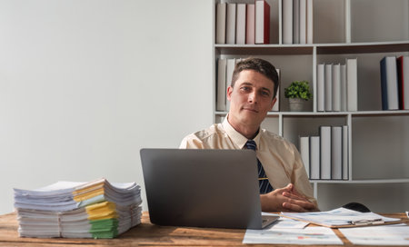 Portrait of a confident businessman sitting at a desk in the office. Using a laptop computer....