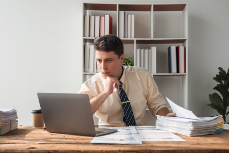 Unhappy young businessman feeling bored and stressed at work looking at laptop with hopeless...