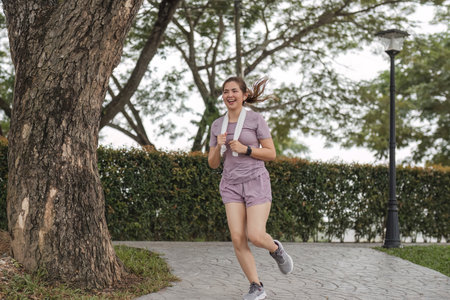 Young beautiful Asian woman jogging at the park in the morning, health and exercise concept.の写真素材