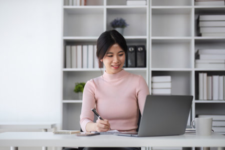 Young Asian woman uses laptop to complete financial transactions, financial planning and investments through online banking.の写真素材