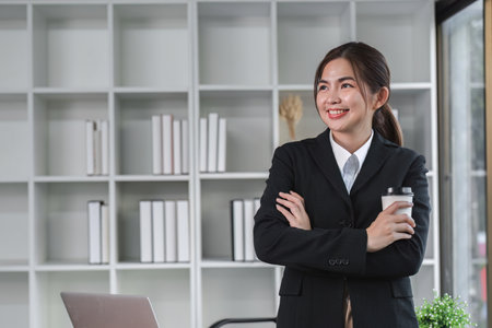 Portrait smiling Asian business woman uses laptop to work on financial transactions. Planning work on the desk in the officeの写真素材