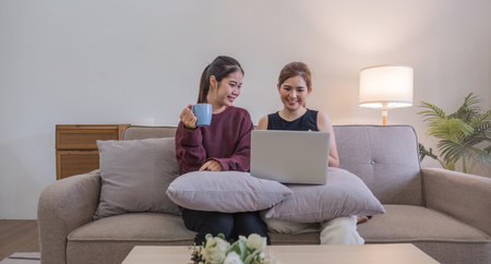 Two women communicate with friends and classmates via video link using laptop and smartphone in...