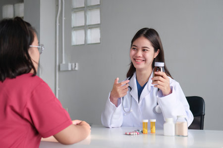 An Asian female doctor is consulting a patient who comes to discuss taking medication for health care. and treat disease with medicineの写真素材