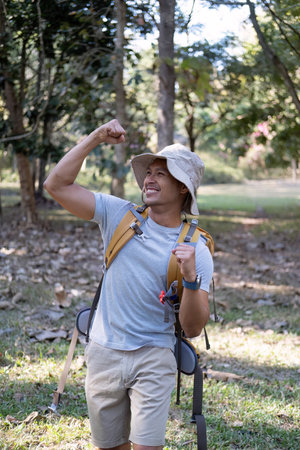 Portrait of a happy smiling Asian tourist, 30-35 years old, backpacking in a national park. asian male tourist enjoying his hiking trip Nature activities, holidays, outdoor hobbies.の写真素材