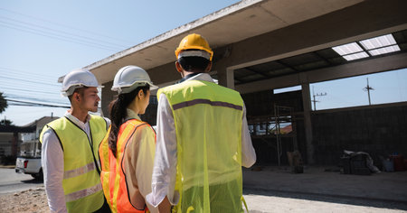 Team of professional civil engineers and architects holding project plan paper, supervising and...
