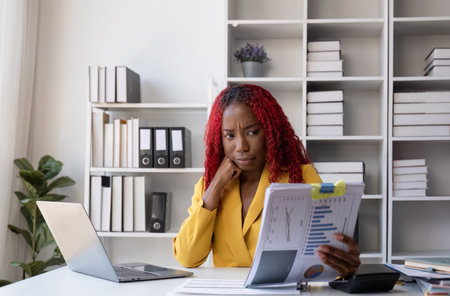 Young African American business woman uses a calculator to calculate numbers. Company financial...