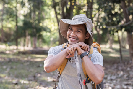 A middle-aged Asian tourist smiled happily. Backpacking in the national park Asian male tourist enjoying his hiking trip nature activities holiday outdoor activitiesの写真素材