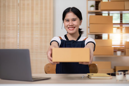 A young Asian entrepreneur sells product online through an online platform and pack product into shipping boxes.の写真素材