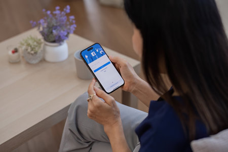 CHIANG MAI, THAILAND - FEB 27 ,2024: Woman holding Iphone 14 with Facebook application on the screen. Facebook is a popular online social networking service.のeditorial素材