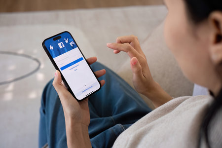 CHIANG MAI, THAILAND - FEB 27 ,2024: Woman holding Iphone 14 with Facebook application on the screen. Facebook is a popular online social networking service.のeditorial素材