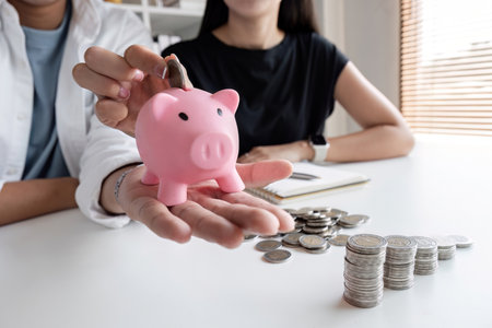 A committed Asian couple saves money together. Counting the coins in the piggy bankの写真素材