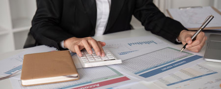 Close up, A young accountant calculates financial figures and company spending graphs using a...