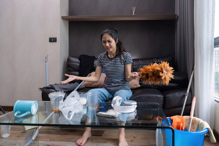 Beautiful young Asian woman feeling tired and stressed after doing housework. She was sitting on the...
