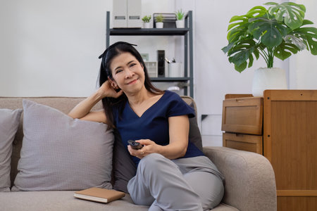 Elderly womans leisure day watching TV, relaxing on the sofa in the living room.