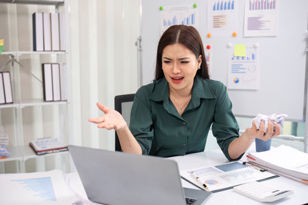 Young businesswoman is having problems with her work. Feeling stressed and unhappy because work results do not meet goalsの写真素材