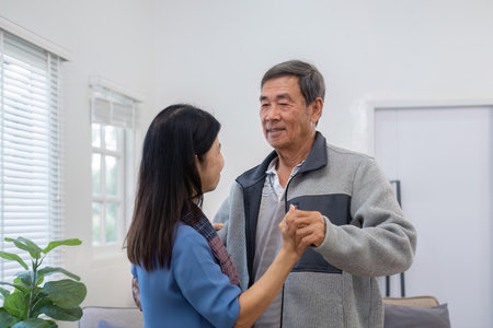 An elderly couple in their 60s happy danced together in the living room.