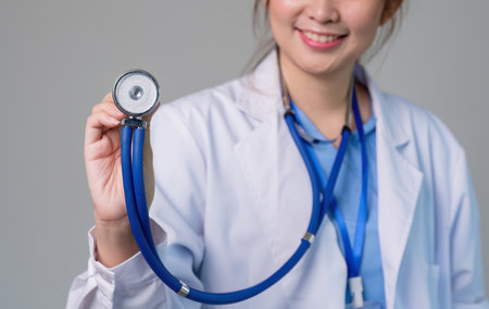 Confident female doctor standing holding stethoscope in clinicの写真素材