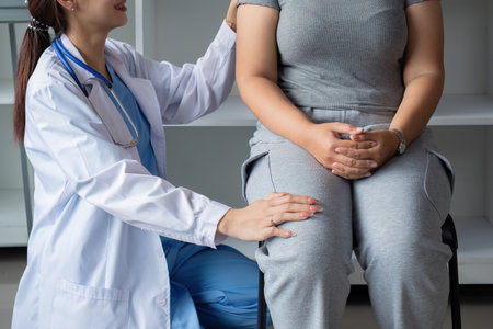 Female doctor and elderly female patient consulting about health problems in clinicの写真素材