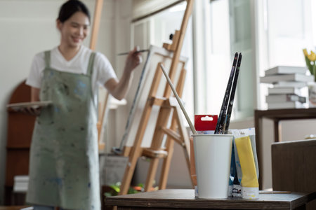 Young Asian female artist is intently painting acrylic paints on canvas in a painting studio.の写真素材
