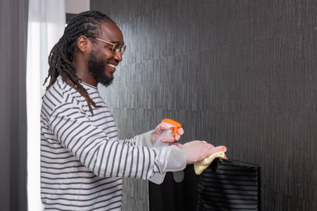 African man in casual clothes Clean dust or dirt in the room. Stand holding cleaning supplies and...