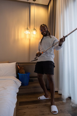 Playful African man in casual clothes Clean the dust or dirtiness of the room happily and have fun cleaning.の写真素材