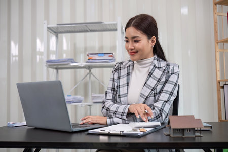 Real estate agents discuss and show model homes to clients online via laptops to finalize deals and sign home contracts.の写真素材