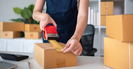 Small business owners who sell online use duct tape to package their products and prepare them for delivery to customers.の写真素材
