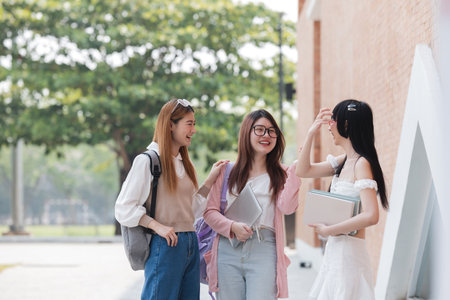 Happy Asian teenager female college student holding book and looking at nature outdoors at university Prepare for classの写真素材