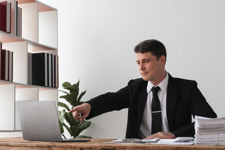Businessman pointing at laptop screen in office, concept of focus and direction