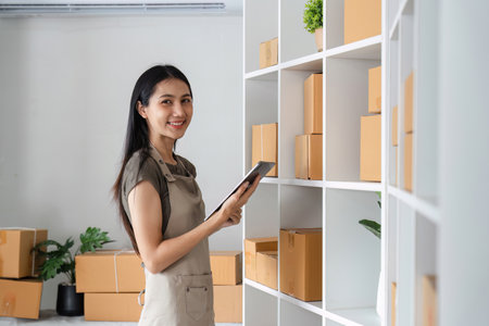 Portrait of a Smiling Entrepreneur Organizing Products for Online Sales in a Modern Home Office Settingの写真素材