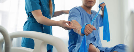 Elderly Patient Receiving Physical Therapy from Young Female Therapist Using Resistance Bands in...