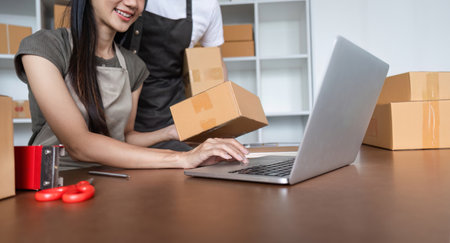Online Selling Couple Taking Order and Packing Product in Home Officeの写真素材