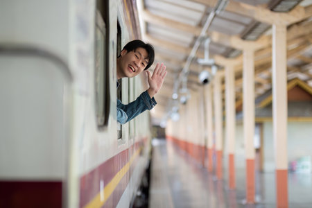 Young Man Waiting for the Train at a Modern Train Station with Urban Architecture and Natural Lightingの写真素材