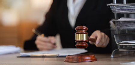 Female Lawyer Reviewing Contract Documents for Legal Case in Office Setting with Gavel on Desk