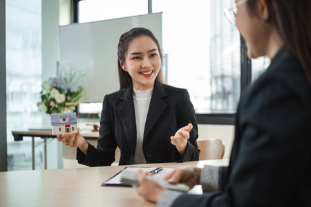Real Estate Agents Discussing Home Buying and Selling Contracts in Modern Office Settingの写真素材