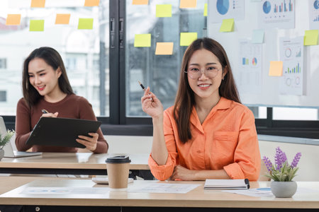 Young Businesswoman Working Relaxed in a Modern Office Environment with Colleagues and Creative Workspaceの写真素材