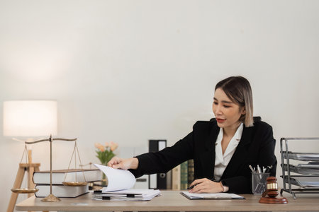 Professional Female Lawyer Working at Desk in Modern Office with Legal Documents and Scales of...