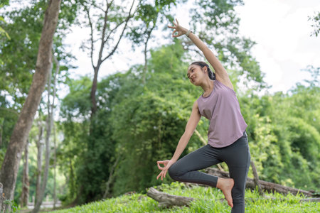 Young Healthy Woman Practicing Yoga Outdoors in a Lush Green Park, Embracing Nature and Wellness