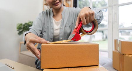 Young Woman Packing Orders for Her Online Small Business from Home Officeの写真素材