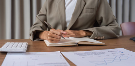Professional Business Team Taking Meeting Notes During a Collaborative Office Meeting with Financial Documents and Calculatorの写真素材